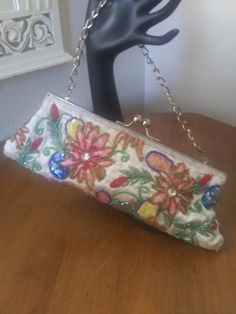 "Vintage beaded floral satin evening clutch. Embroidered, beaded and sequined flowers on white satin. Has a short silver-tone chain which can be tucked inside to use purse as a clutch, has Silver-tone ball latch at top. Inside is in fair vintage condition. Very clean, but there is a 3\" streak of rust stain at the top inside, where metal must have gotten damp and stained the lining. (See photo). Beading and sequins are perfect, no fraying or loose threads despite its 40 plus years!" White Evening Bag For Spring Party, Embroidered Clutch For Evening In Summer, Vintage White Clutch For Party, Spring Evening Clutch Embroidered, Vintage White Embellished Evening Bag, Spring Evening Embroidered Clutch, Embellished Clutch For Summer Evenings, Spring Party Beaded Clutch, Multicolor Clutch For Evening In Spring