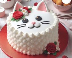 a cake with white frosting and red roses on it, decorated like a cat