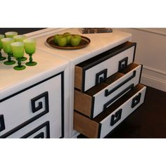 a white dresser with drawers and green glasses on top