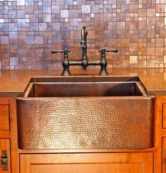 a kitchen sink with two faucets on the side and brown cabinets in front