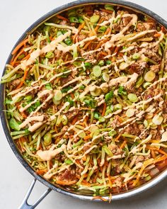 a skillet filled with meat and veggies on top of a white table