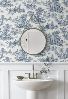 a white sink sitting under a mirror next to a wall