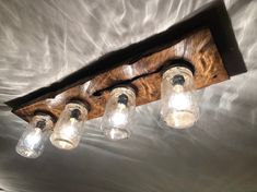 a wooden light fixture with five glass jars hanging from it