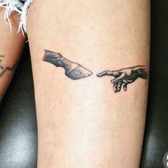 two hands touching each other with tattoos on their arms and legs, one holding the other's hand