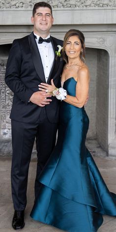 a man in a tuxedo and woman in a gown pose for a photo