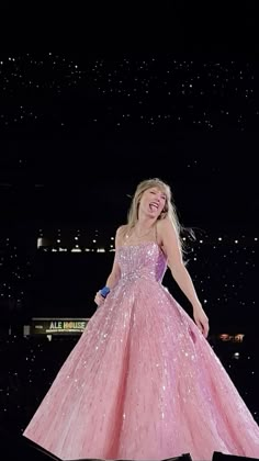 a woman in a pink ball gown standing on top of a stage with her hands behind her back