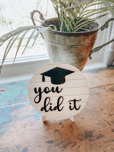 a wooden sign that says you did it next to a potted plant