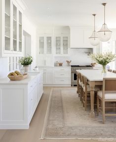 a kitchen with white cabinets and an island in the middle, along with a rug on the floor