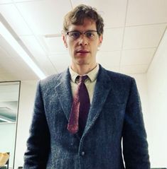 a man in a suit and tie posing for the camera with his hands in his pockets