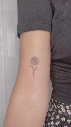 a woman's arm with a small flower tattoo on the left side of her arm