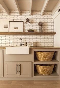 a kitchen with white brick walls and wooden shelves above the sink is filled with baskets