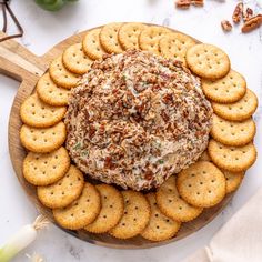 a platter filled with crackers, cheese and nuts on top of a wooden board