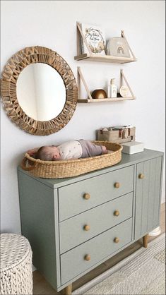 a baby sleeping in a crib next to a wall mounted mirror and shelf above it