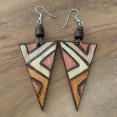 two triangle shaped wooden earrings with wood bead earwires on top of a wooden table