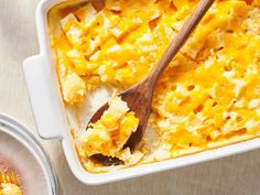 a casserole dish with cheese on top and a wooden spoon next to it