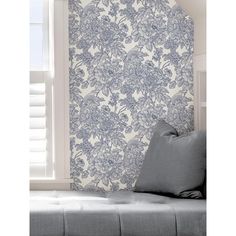 a blue and white floral wallpaper in a living room with a gray couch next to it