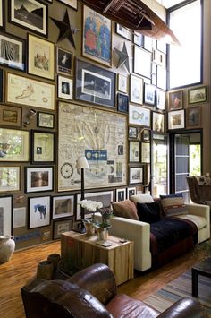 a living room filled with furniture and lots of framed pictures on the wall above it