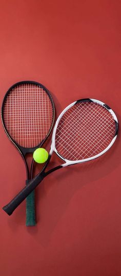 two tennis rackets and a ball on a red background