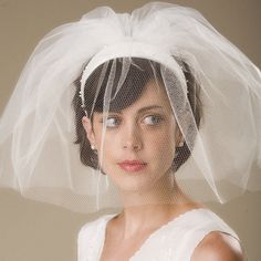 a woman wearing a veil over her head with a white dress and hat on it