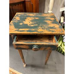 an old wooden table with yellow paint on it's top and bottom drawer open