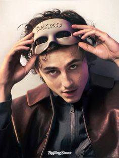 a young man wearing a leather jacket with a mask on top of his head and writing on the side