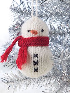 a knitted snowman ornament hanging from a christmas tree