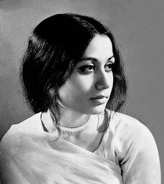 black and white photograph of a woman with long hair wearing a pearl necklace, looking off to the side