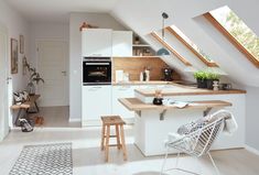 an open kitchen with white cabinets and wooden counter tops, along with stools in the foreground