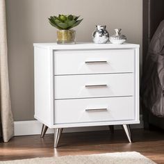 a white nightstand with two drawers and a potted plant