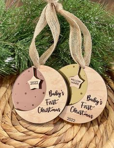 three wooden christmas ornaments hanging from a basket with pine branches in the background and baby's first christmas ornament on top