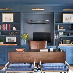 an office with blue walls and built in bookshelves, leather chairs, and a wooden desk