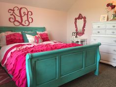 a bed with pink and green sheets in a bedroom next to a white chest of drawers