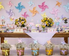 a table topped with lots of cakes and cupcakes covered in frosting next to small baskets filled with flowers