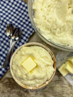 a bowl of mashed potatoes with butter on the side next to a spoon and blue checkered napkin