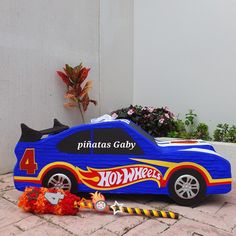 a blue toy car sitting on top of a brick floor next to a potted plant