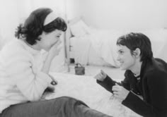 two young women sitting on top of a bed next to each other in black and white