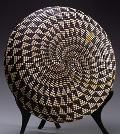 a black and white basket sitting on top of a wooden stand