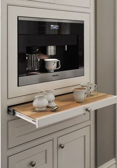 a microwave oven sitting on top of a counter next to cups and tea kettles