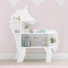 a child's desk with books and toys on it in front of a pink wall