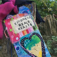 a colorful book with words on it sitting on top of a wooden fence next to trees