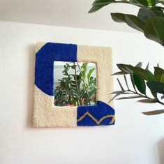 a mirror hanging on the wall next to a plant in a potted planter