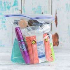 a clear bag filled with various items on top of a white wooden table next to an orange and blue toothbrush