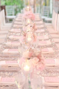 a long table is set with pink flowers and place settings for the guests to sit at