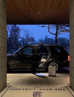 a black suv parked in front of a building with the door open to another car