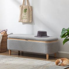 an orange cat laying on the floor next to a gray bench with a bag hanging from it