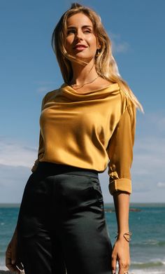 Exquisitely designed to captivate, this elegant cowl neck blouse wraps you in a soft, lustrous embrace, flowing gently over your curves with romantic grace. Versatile and refined, this timeless beauty effortlessly transitions from daytime sophistication to evening allure, bringing a subtle touch of luxury to every moment, whether bathed in sunlight or candlelight. Cowl neck with elegant drapes and subtle bell cuffs. Detailed with exquisite gold button hardware. Hits just below the hips with side Cashmere Winter Scarf, Silk Slip Skirt, Silk Pjs, Silk Tee, Cashmere Pants, Silk Cami, Cashmere Beanie, Silk Pajama Set, Bow Blouse