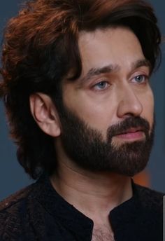 a close up of a person with a beard and black shirt looking off to the side