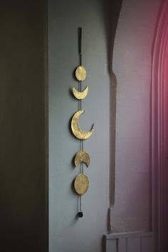 a clock with three phases hanging from it's side next to a pink wall