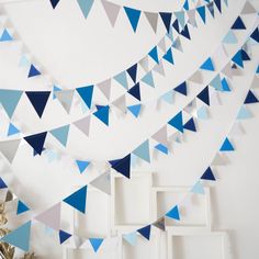 blue and white paper flags hanging from the ceiling in a room with pictures on the wall