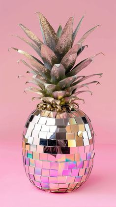 a pineapple sitting on top of a disco ball covered in mirror tiles and leaves